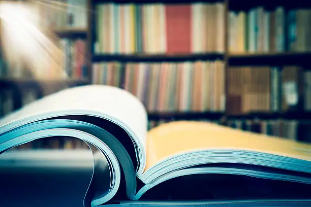 Photo of Piles of books and magazines on background of book shelf