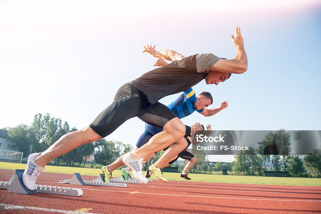 Runners preparing for race at starting blocks Runners preparing for race at starting blocks. Sprinting Stock Photo