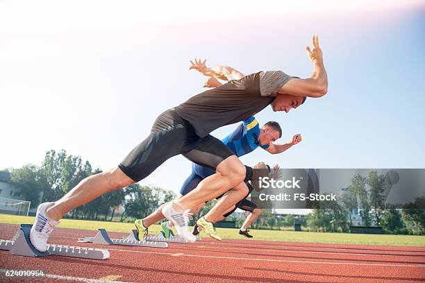 Runners Preparing For Race At Starting Blocks Stock Photo - Download Image Now - Sprinting, Sprint, Starting Line