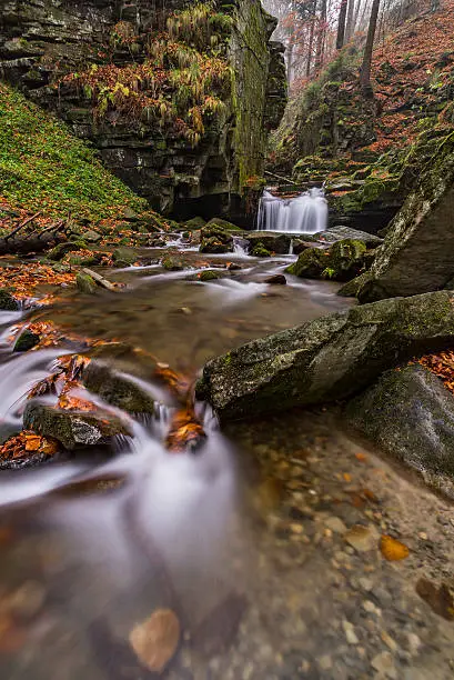 View of autumn stream with waterfalls with stones