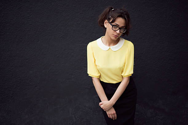 Cute, caucasian, retro styled young woman standing and leaning on the wall