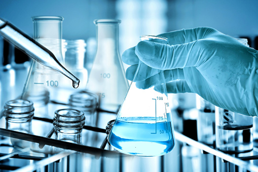 Flask in scientist hand with laboratory background, science research and development concept.