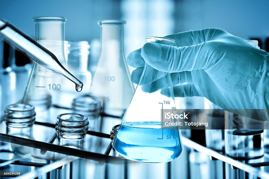 Flask in scientist hand with laboratory background Flask in scientist hand with laboratory background, science research and development concept. Chemistry Stock Photo