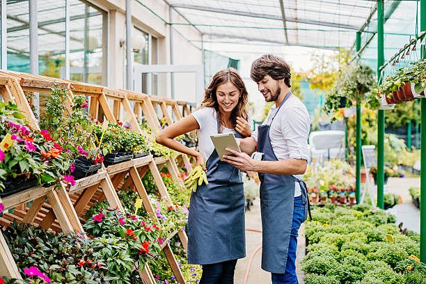 Couple of gardeners with digital tablet Smiling young couple working in garden center looking at a digital tablet. companion plants stock pictures, royalty-free photos & images