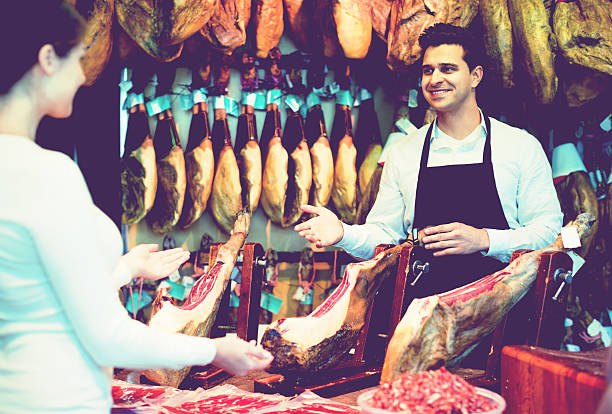 istock Young cheerful brunette choosing iberico and serrano jamon 624047762