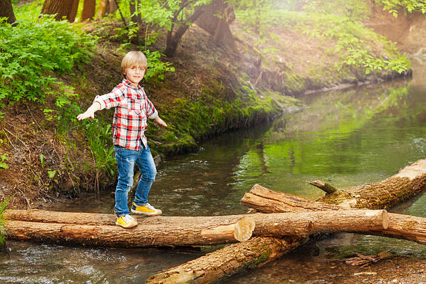 istock Happy boy crossing a river in the forest 624054982