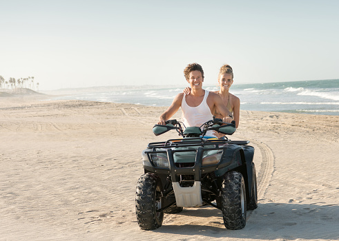 Couple riding a Off-Road Vehicle ATV Quad down the Beach. Candid Smiles. North Brazil. Nikon D810. Converted from RAW.