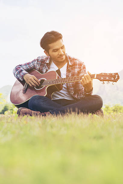 istock Handsome man playing guitar on green grass 624083700