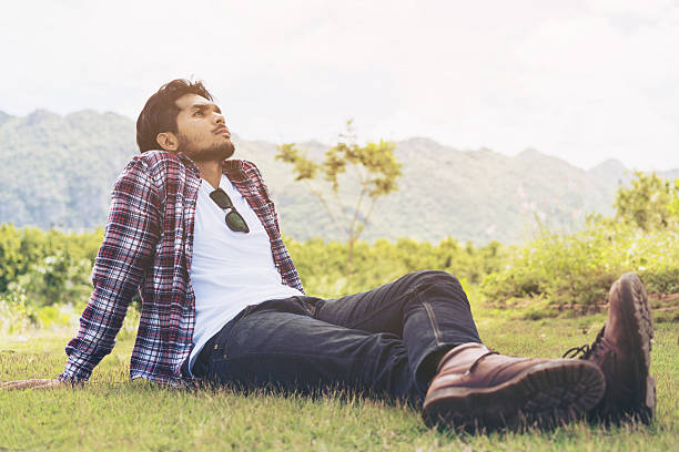 istock Young man sitting on green grass thinking 624084462