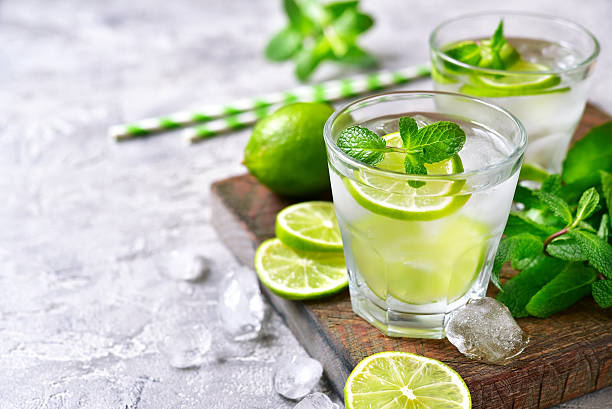 Cold refreshing summer lemonade mojito. Cold refreshing summer lemonade mojito in a glass on a grey concrete or stone background. tonic water stock pictures, royalty-free photos & images