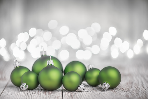 Green Christmas Balls on White Rustic Wood Board and Defocused Christmas Lights
