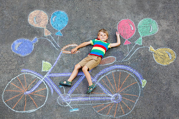 istock little kid boy drawing bicycle chalks picture on ground 624100722