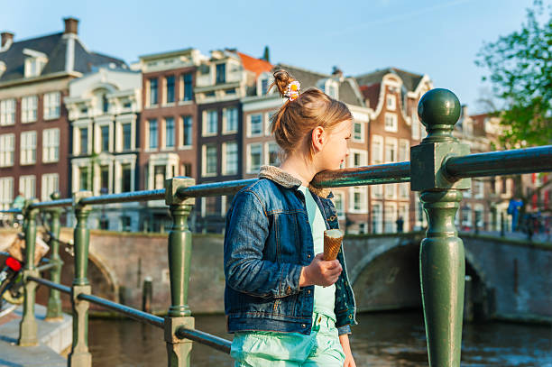 Outdoor portrait of a cute little girl looking on a beautiful canal in Amsterdam