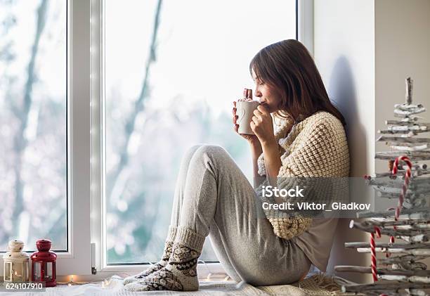 Young Beautiful Woman Drinking Hot Coffee Sitting On Window Sill Stock Photo - Download Image Now