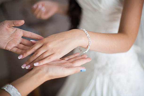 Bride wrapping pearl bracelet on hand, closeup