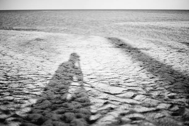 istock man's shadow on a sand beach ,blurred sea in background 624110204