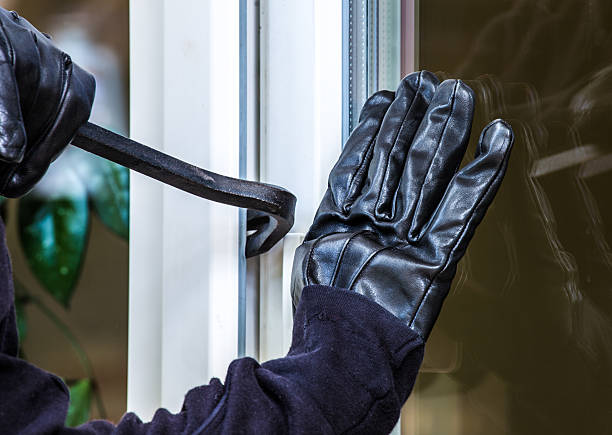 Burglary into a house A burglar opens a window with a breaker. He wears gloves and lifts the window. burglary stock pictures, royalty-free photos & images