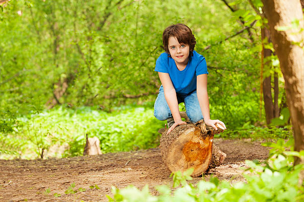 istock Cute young boy posing on the log in summer park 624112894