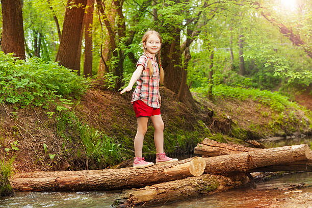 istock Happy girl crossing a river in the forest 624115520