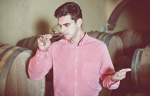istock Male customer tasting red wine from wooden barrels 624117362