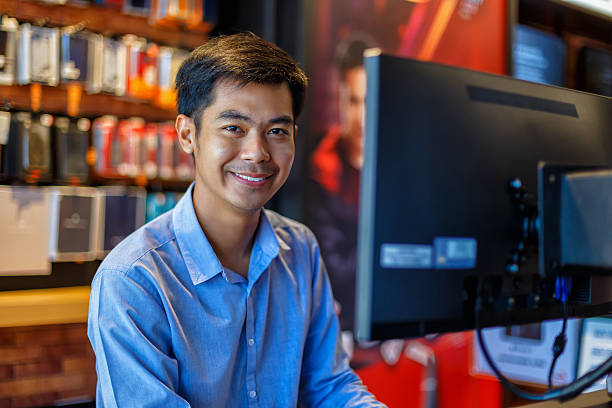 homem asiático jovem bonito usando computador no escritório - men human hair portrait human eye - fotografias e filmes do acervo