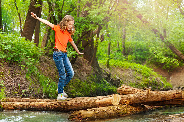 istock Cute girl balancing while crossing a log bridge 624118434