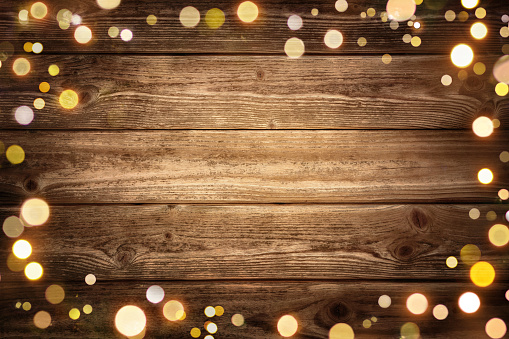 Festive rustic wood background with dark vignette and framed by glowing bokeh lights, ideal for Christmas, advertisement or party