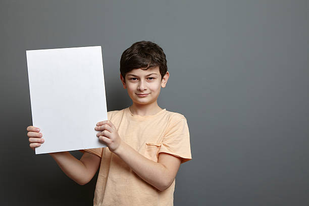 istock Cute boy is holding a blank page near his head 624124272