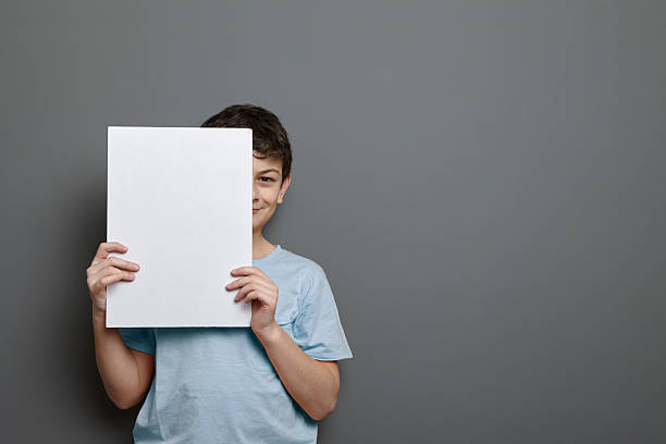 Cute boy is holding a blank page near his head