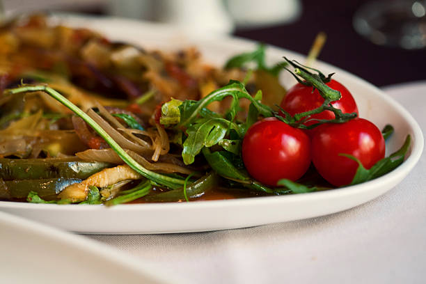 Cherry tomato and rocket salad on a plate, with some grilled vegetables