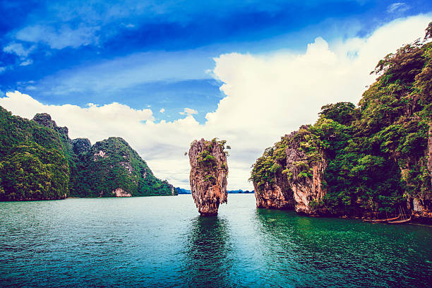 James Bond Island in Phang Nga Bay, Thailand Phang nga, Ko Tapu, Thailand also known as James Bond Island, Phuket, Thailand. Visible are dramatic cloudscape over the Andaman Sea, pure turquoise water and really large cone rock in the middle of the bаy.  karst formation photos stock pictures, royalty-free photos & images