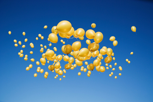 Large group of golden balloons in clear sky