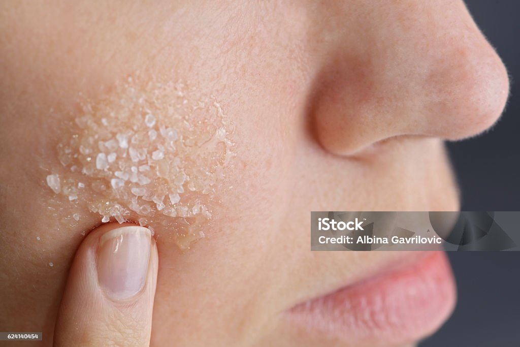 Woman applying homemade facial scrub from honey and sea salt Woman applying homemade facial scrub from honey and sea salt. Skin care concept Exfoliation Stock Photo