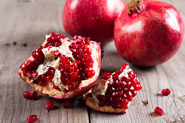 istock Whole and broken red ripe juicy pomegranates on rustic wooden 624147544