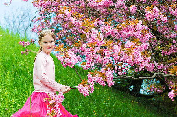 istock Smiling little girl posing next to a japanese cherry tree 624147962