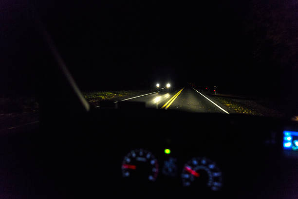 route rurale approche nocturne des phares des véhicules - road reflector photos et images de collection