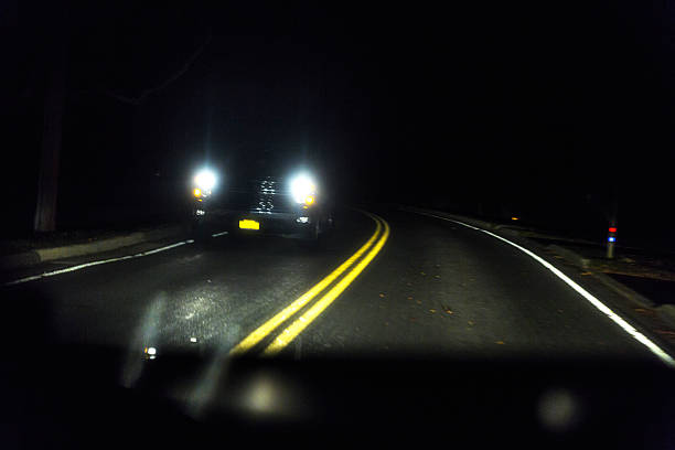 phares de véhicules à l’approche sur la courbe de route de nuit rurale - road marking road reflector road dividing line photos et images de collection