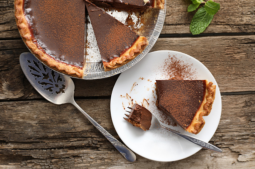 An overhead close up horizontal photograph of a partially eaten slice of chocolate mint pie with another slice in the waiting.