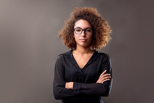 young curly-haired woman with her arms folded in casual workwear is a manager waiting for your audit