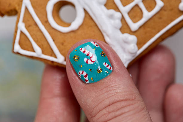 Christmas gingerbread cookie in female hand. Female hand with festive  Christmas manicure  holding tasty gingerbread cookie. Christmas and New Year. christmas nails stock pictures, royalty-free photos & images