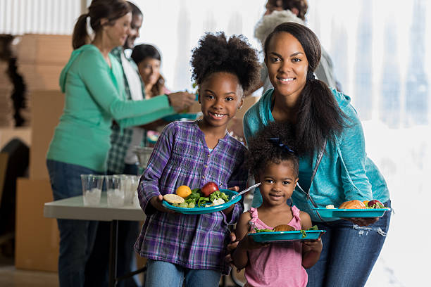 istock Pretty African American mom and daughters at soup kitchen 624178604