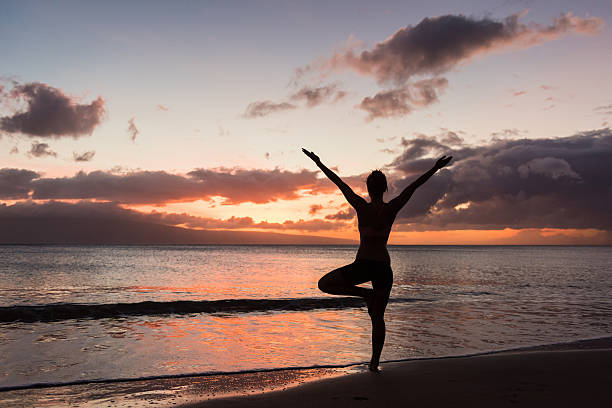Woman practicing beach yoga at sunset