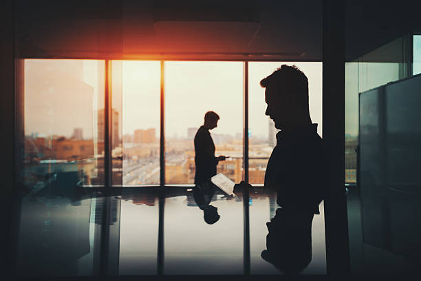 istock Silhouette of two businessmen in office interior 624179928