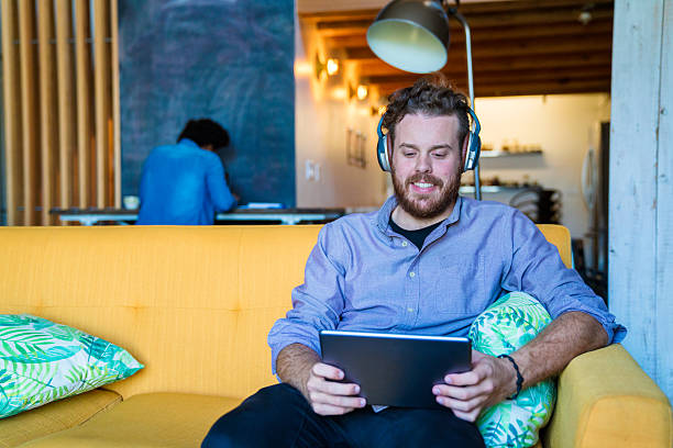 istock Young man wearing headphones and using a digital tablet 624181712