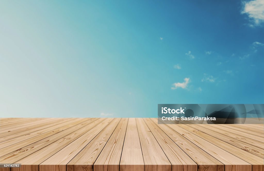 Wood table top on gradient blue sky and white clouds Wood table top on gradient blue sky and white clouds background. also used for display or montage your products Floorboard Stock Photo