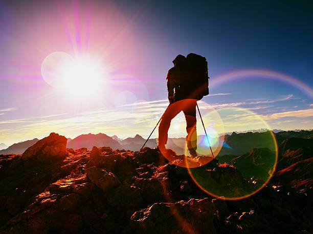 istock Lens flare defect.Man hiker with rucksack walk  on rocky peak 624196406