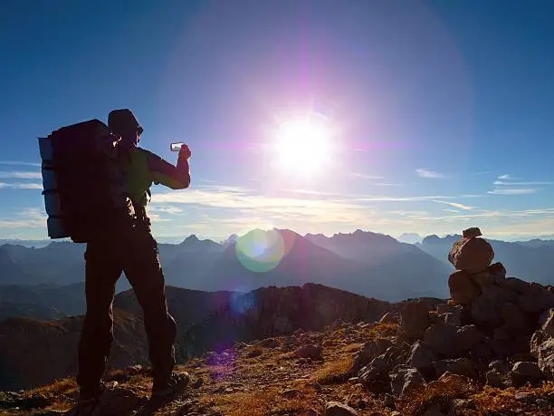 Photo of Lens flare defect. Hiker takes selfie photo with big backpack