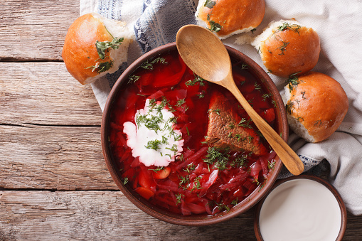 Ukrainian borsch soup and garlic buns on the table. Horizontal view from above