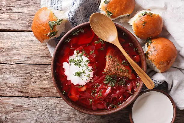 Ukrainian borsch soup and garlic buns on the table. Horizontal view from above