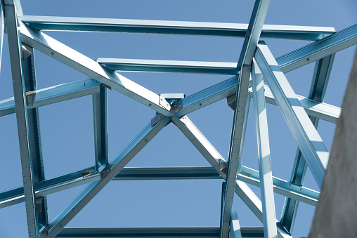 Structure of steel roof frame for building construction on sky background.